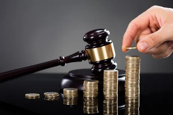 a hand putting coins on top of a gavel