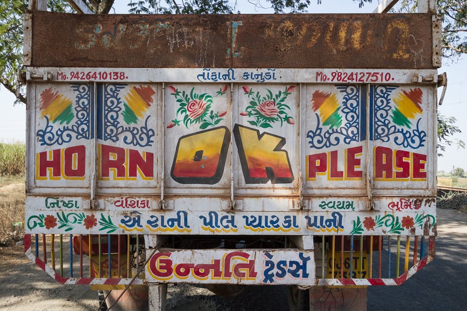 Another back of a truck with the message 'Horn. OK. Please'. Alongwith some other things written in Gujrati language.