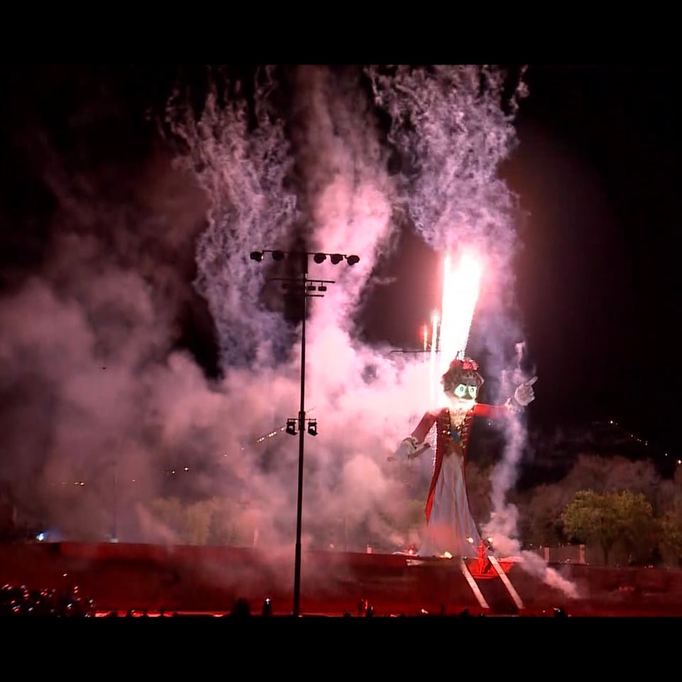 50' puppet named Zozobra on fire, torched by woman Fire Spirit's torches