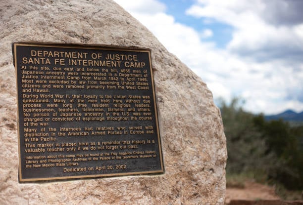 Photo of a plaque embedded in a boulder. Plaque memorializes Santa Fe's Japanese internment camp. Placed as a reminder that history is a valuable teacher only if we do not forget our past.