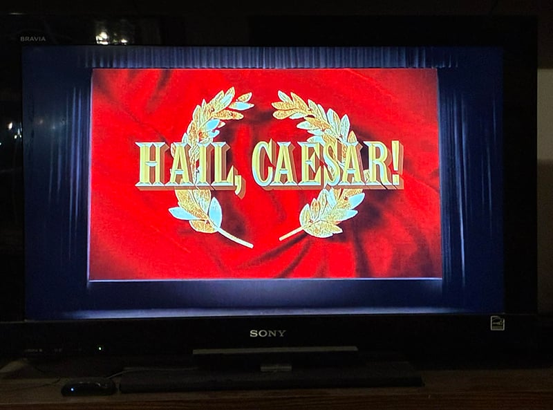 My TV set, paused when the title of the movie Hail, Caesar! came up. The letters are in gold against a red, fabric-y background.