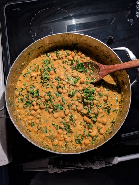 a high-walled pan filled with curried chickpeas and chopped spinach