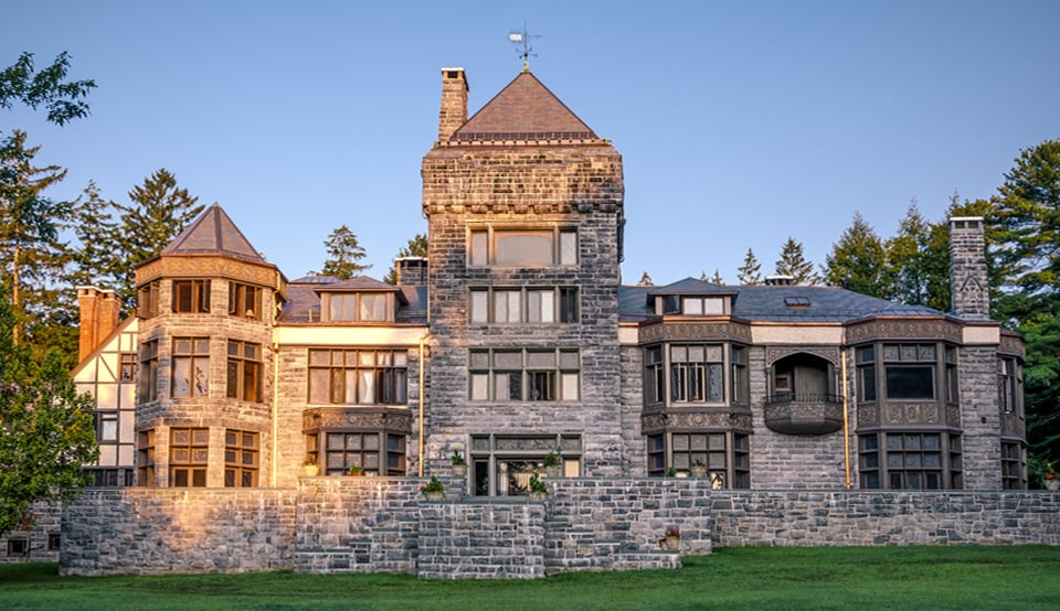 The mansion at Yaddo: a large stone building incorporating Arts & Crafts design, with a three-story tower at the far left, a central tower in the middle, and balconies and bay windows across the front.