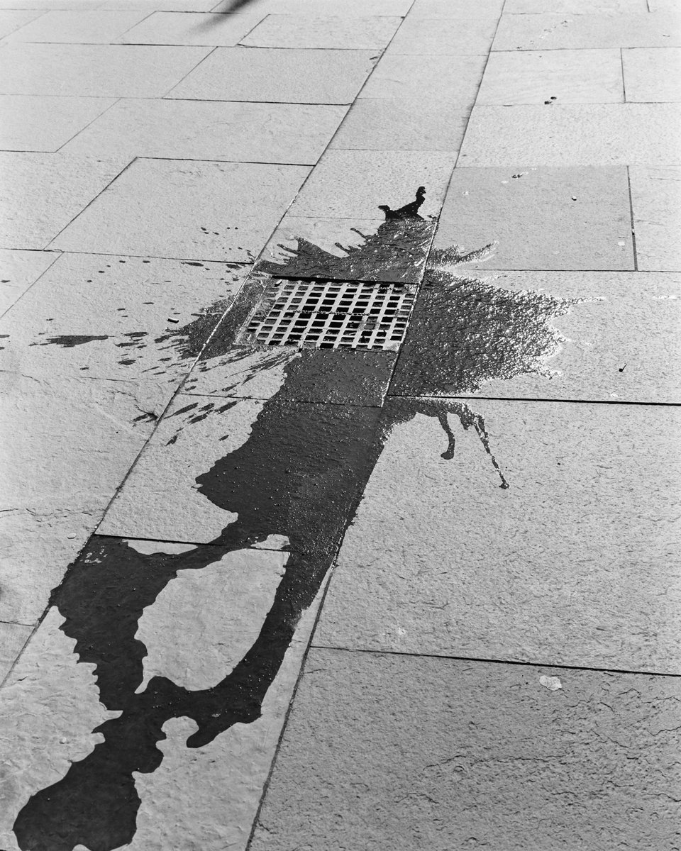 A black and white image of a splash on the pavement that looks like a human