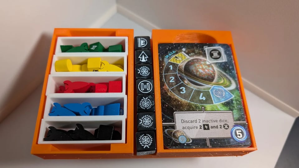 A 3D printed insert for Tiny Epic Galaxies board game. On the left, player tokens are split into small, detachable boxes. In the middle, 7 dice are easy to access and on the right, there's a space for planet cards