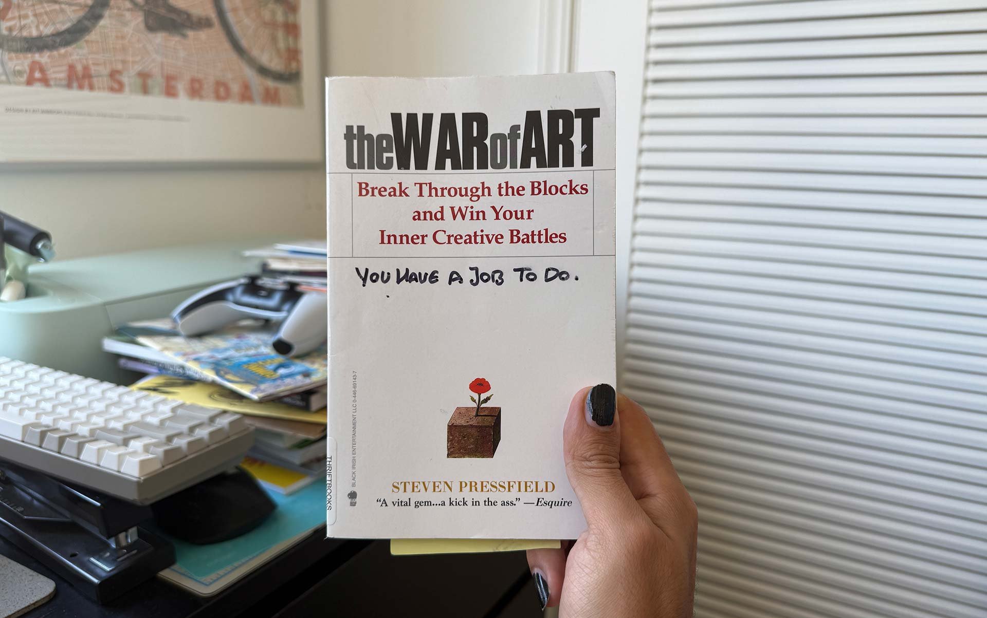 My hand holding up my copy of The War of Art, with my own inscription of you have a job to do, on the cover.