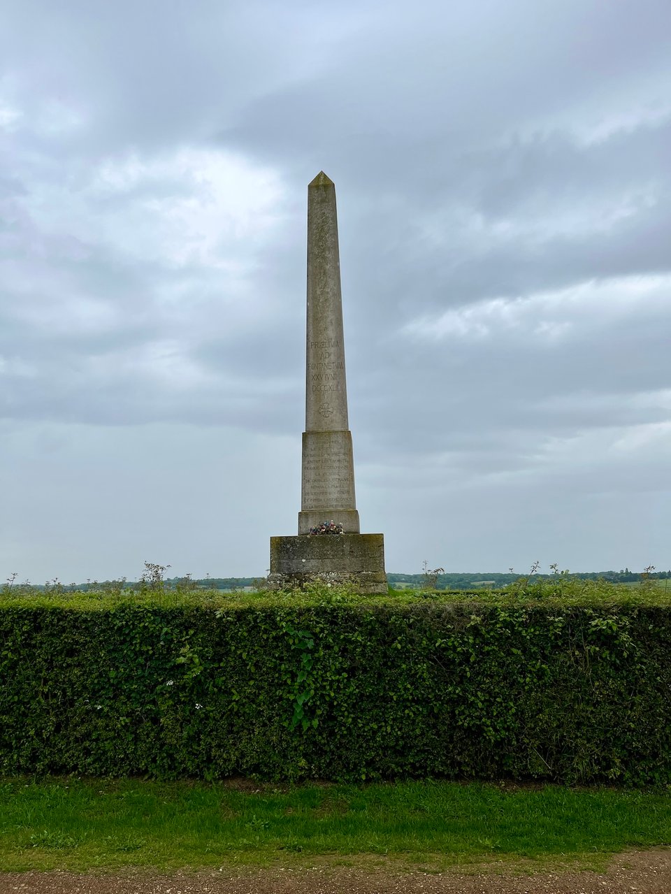 obelisk behind hedge, monument to the battle of fontenoy, grey skies overhead