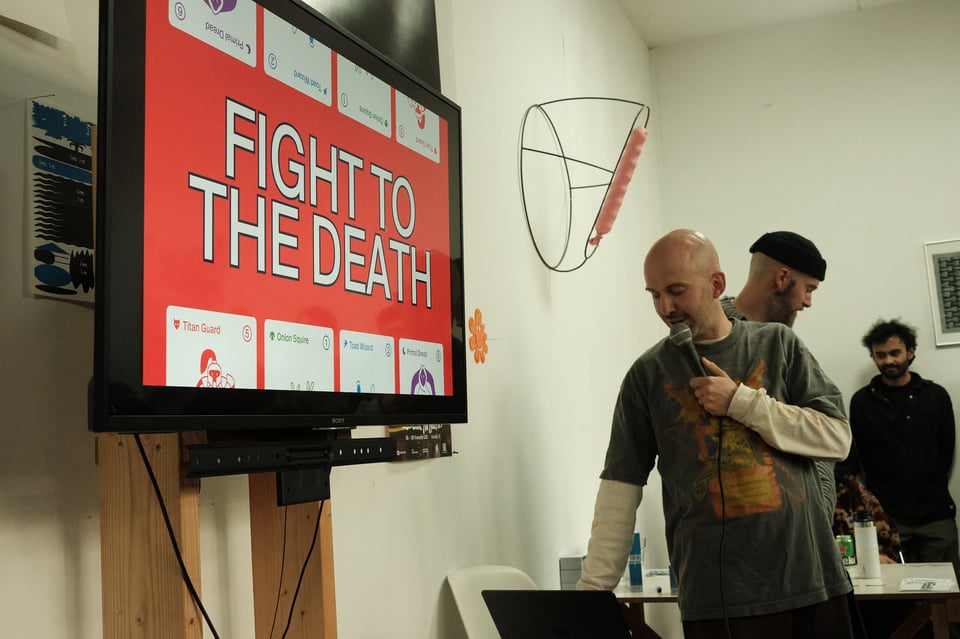 Speaker changes slide on a screen that now says "Fight to the Death"