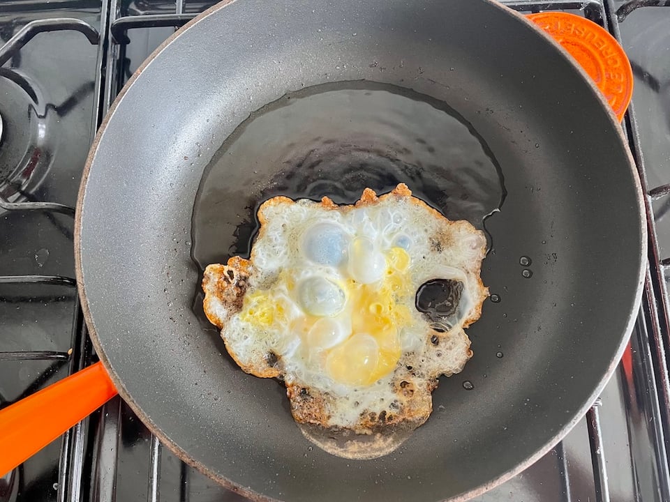 A poorly cracked egg frying