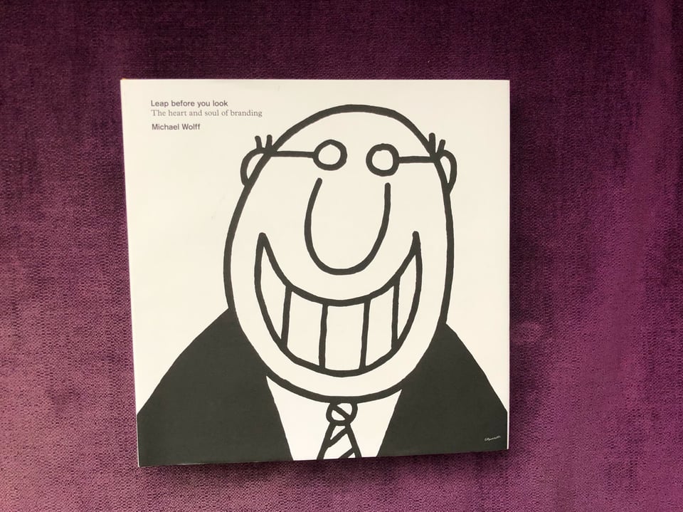 Photograph of the book, "Leap before you look (The heart and soul of branding)" by Michael Wolff. The cover art is a very simple line-drawn cartoon of a bald man with glasses and a wide toothy grin.