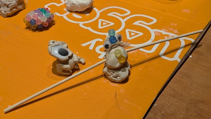 a wider shot of the same two little clay creatures, in which you can see just how flat the first guy's head is, and that the snowman has incredibly long wooden skewers for arms, each at least three times as long as he is tall.