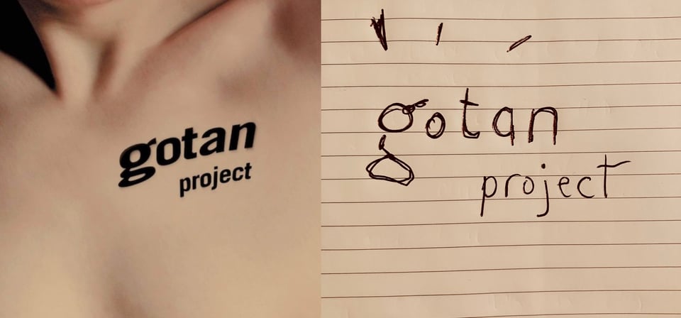 An extreme close up of a white naked person, from the tip of the bottom of the chin to the top of their chest. Almost the entire image is white-pink skin. The image is cropped in such a way that it is indeterminate if the person is male or female. On their left bicep area is "Gotan Project" in black, like a tattoo.