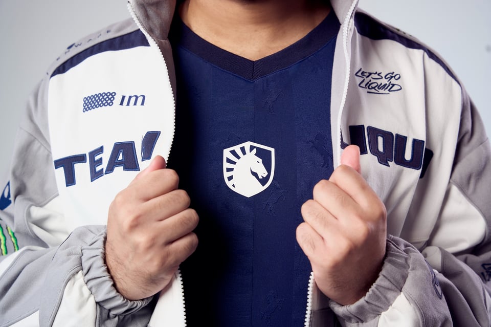 Detail shot of the TL Crest on the new 2026 jersey while hands open up the new Pro Kit Racing Jacket around it.