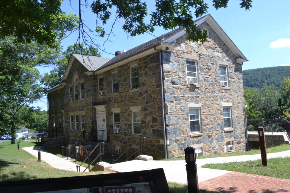 A stone building with a pitched woof and lots of square windows
