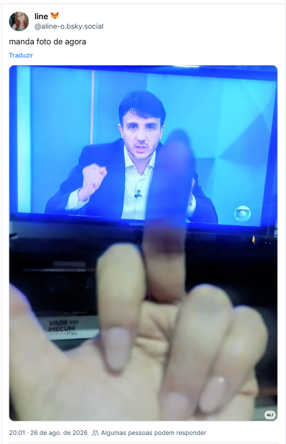 Post de line 🦊 (@aline-o.bsky.social): manda foto de agora
(Renan Santos, de terno, aparece na TV durante transmissão ao vivo, enquanto uma mão faz um gesto obsceno com o dedo médio.)