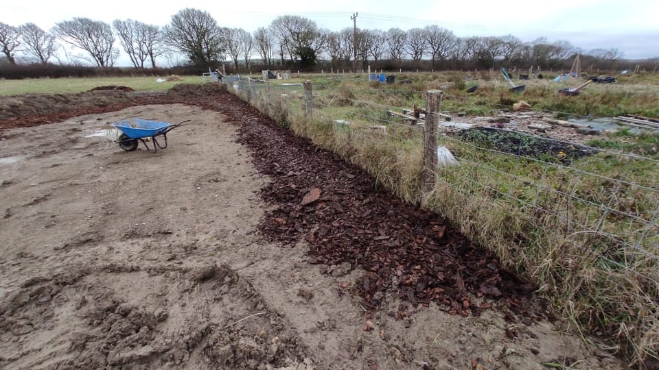What was a field, now deturfed with bark going down one edge of the allotment fence