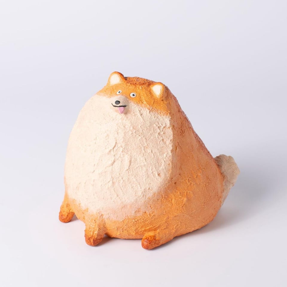 A small sculpture of a very large, round fox with its tongue sticking out