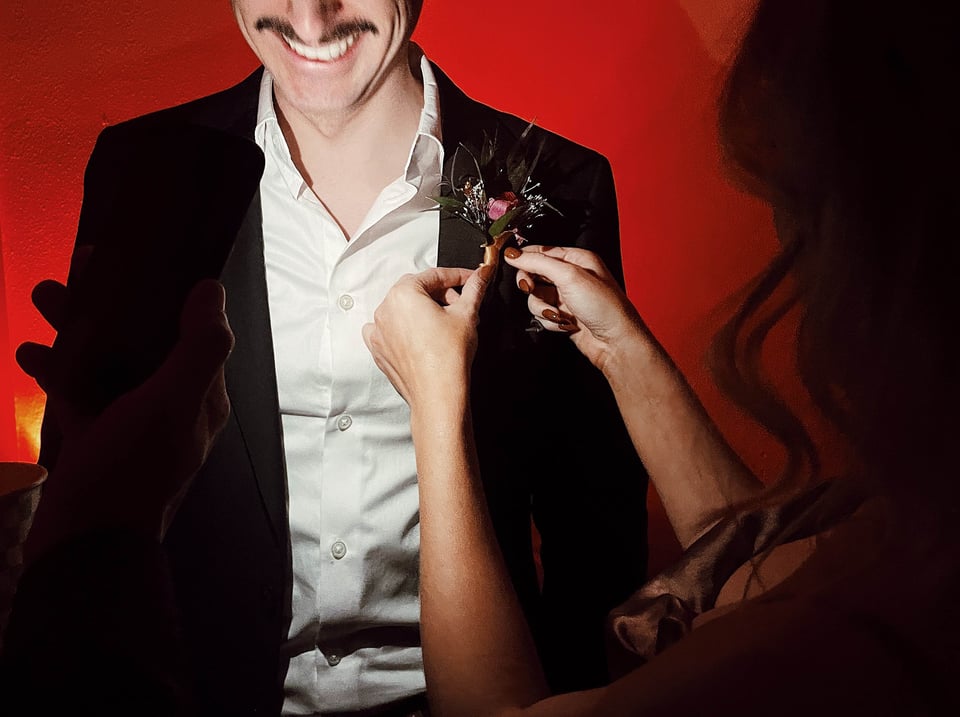 Halie pinning a boutonniere on Ivan.