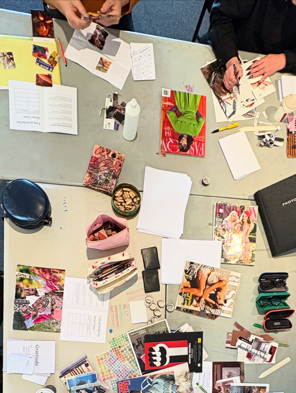 Bird's eye shot of a table of craft - anonymous participant arms and hands working on zines visible.