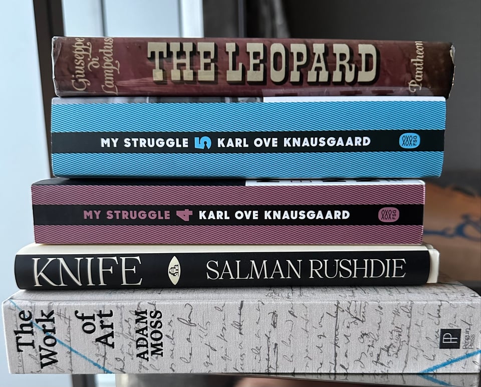 Photo of a stack of books: from bottom, The Work of Art (Adam Moss), Knife (Salman Rushdie), My Struggle, books 4 & 5 (Karl Ove Knausgaard), and The Leopard (Giuseppe di Lampedusa)