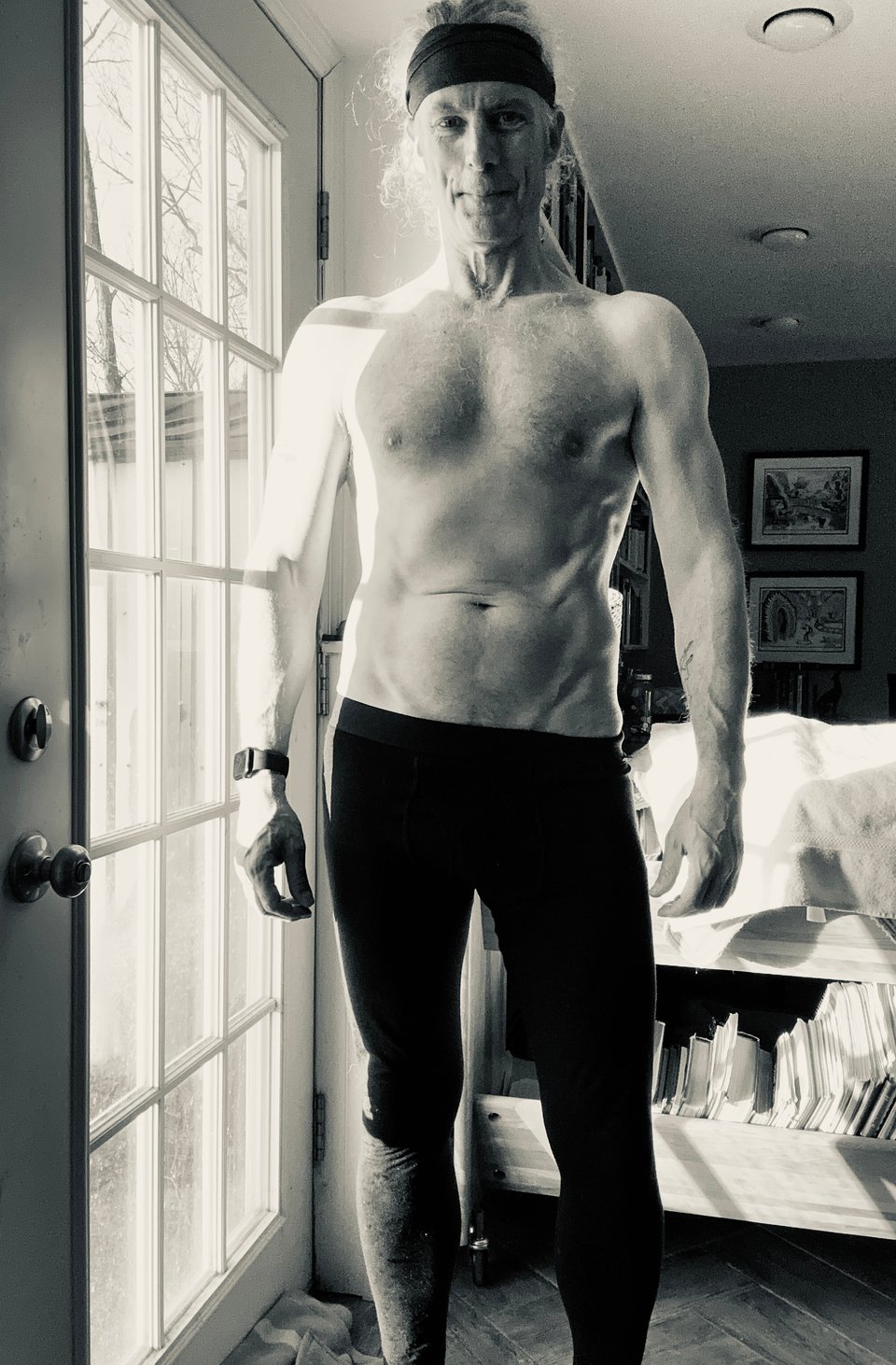 b/w photo of shirtless white man in black tights and a dark grey headband, looking pretty good after a workout.