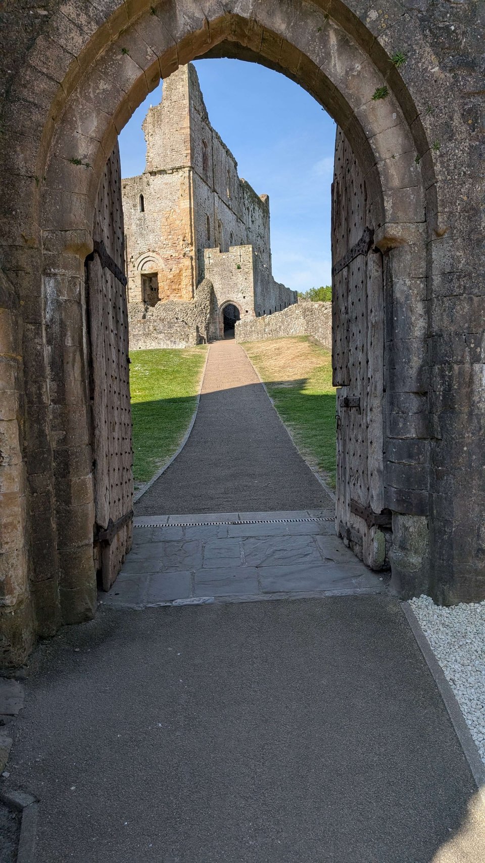 Large wooden gates are open showing the inner courtyards of Chepstow Castle