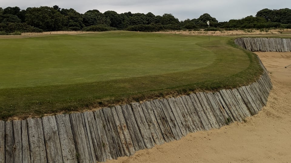 Aldeburgh green from a greenside sleeper-faced bunker running down its right side, tucked back pin