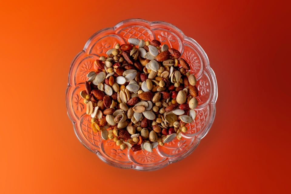 Overhead shot: A bowl of mixed nuts, on an orange backdrop. Photo by Usman Yousaf on Unsplash.