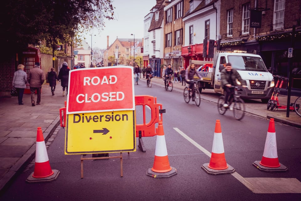 A street blocked by signs that read 'ROAD CLOSED' and 'DIVERSION'. Photo by Ben Wicks on Unsplash.