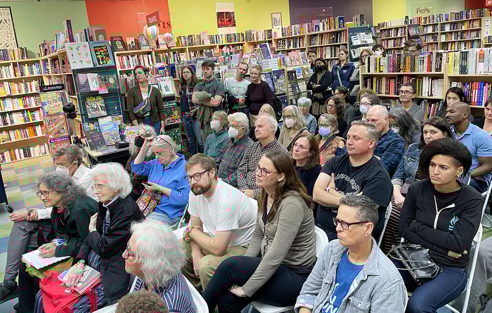 group of people in a bookstore listen to an author read