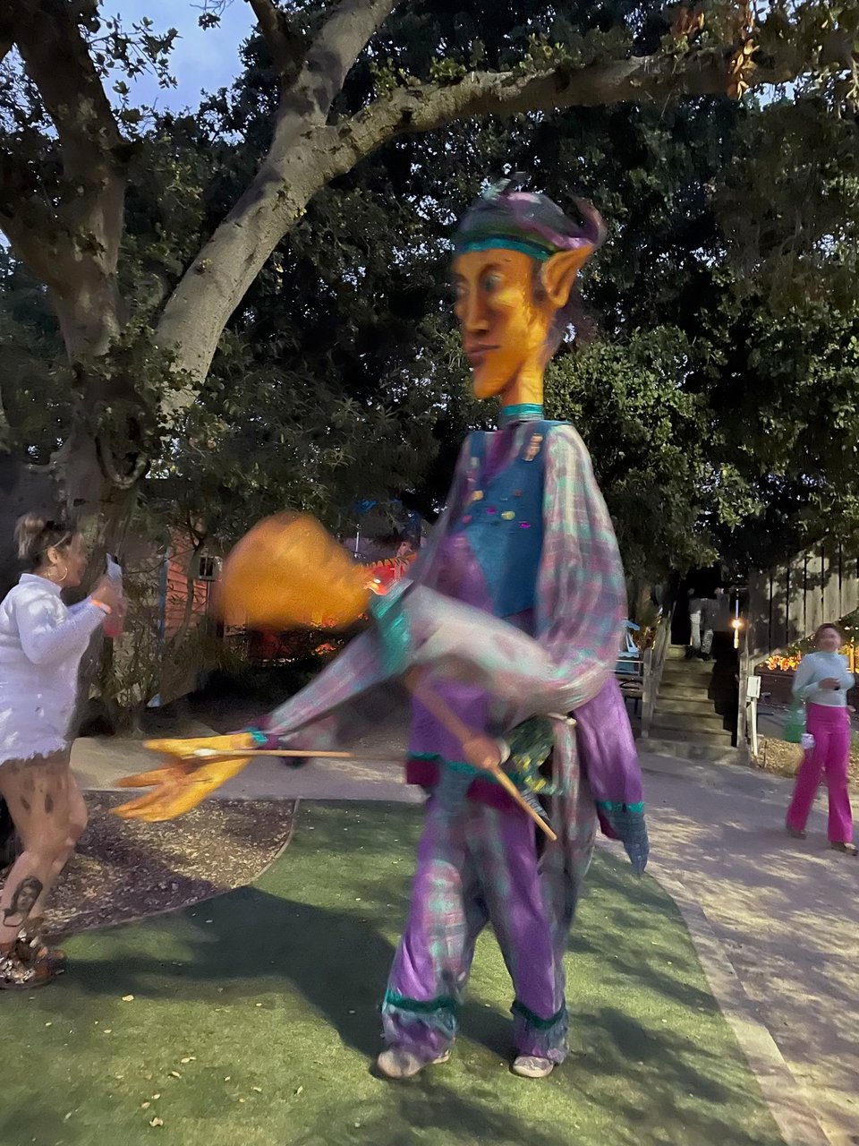 A person in an elf-themed costume waves its gigantic puppeted hands around. Taken at Through the Looking Glass, a music and arts festival held on September 16, 2023 in Oakland, California.