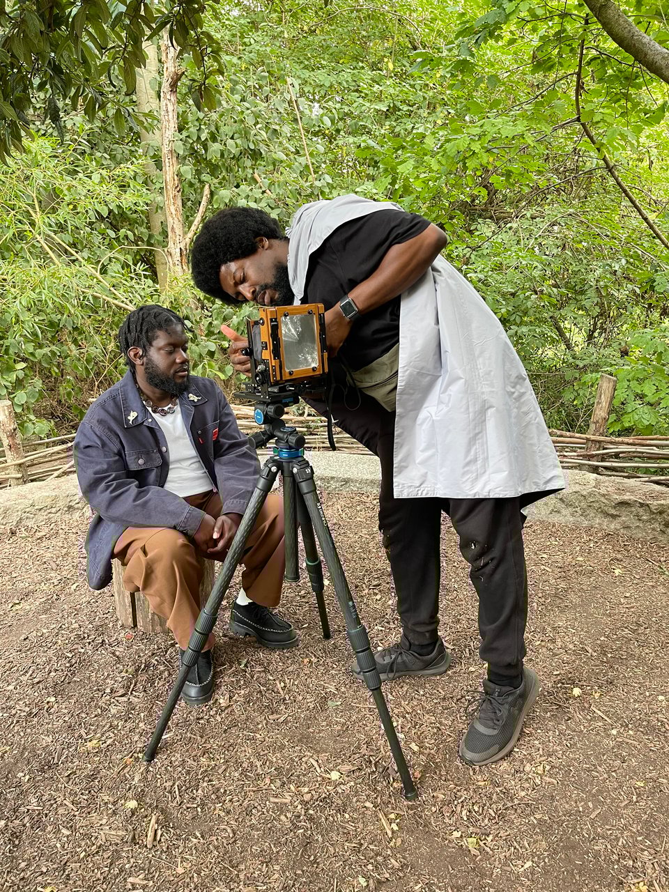 A man prepares to have a portrait made as a photographer prepares the camera