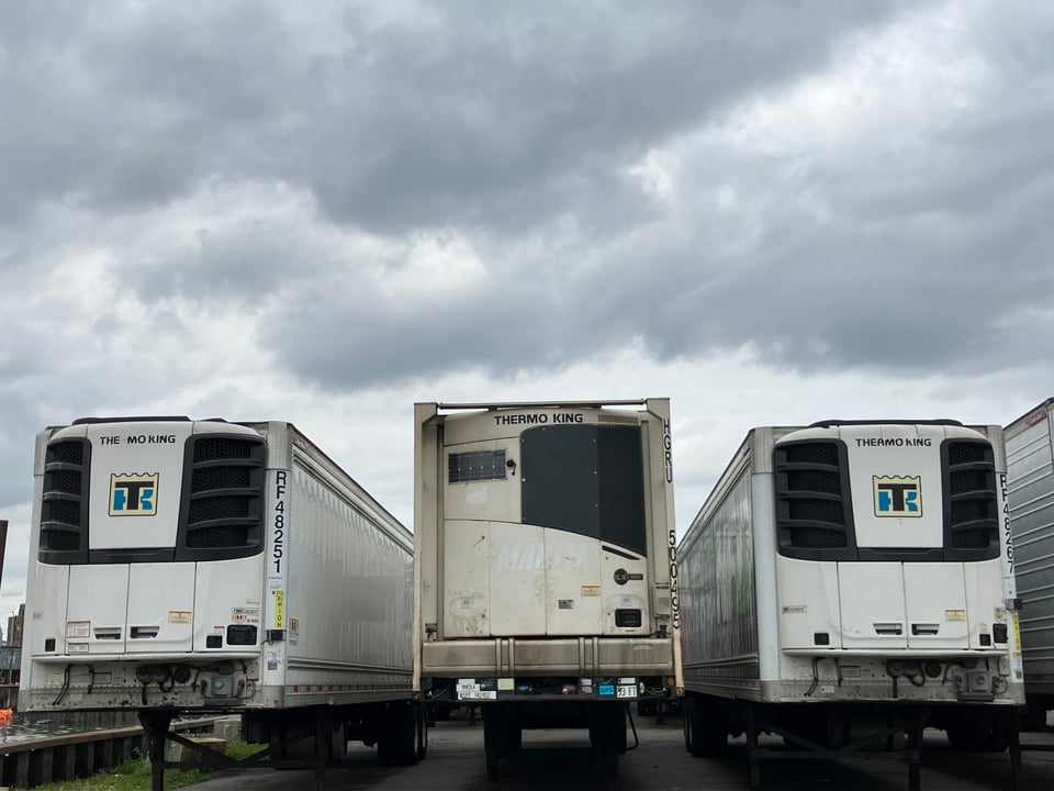 back of three refrigerated trucking trailers printed "THERMO KING" under cloudy sky