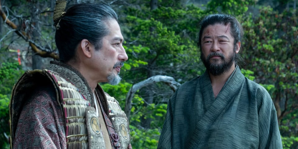 Toranaga and Yabushige talk before Yabushige commits seppuku. Both men are bearded and in robes with a woodland background.