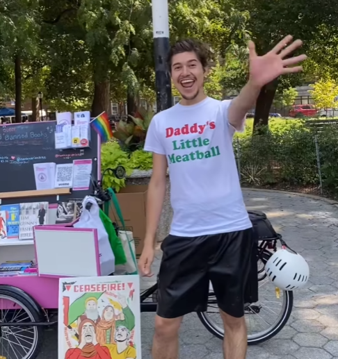Arthur, a white person with dark hair and facial hair wearing a white t-shirt that says
