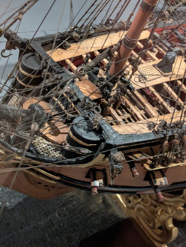 Close-up of a wooden model ship showing barrel-shaped roundhouses