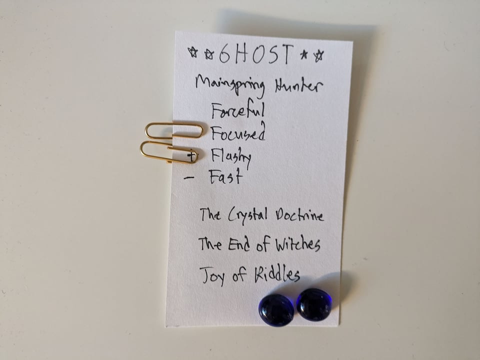 A vertical index card with the character sheet for "Ghost" in Sliver of Fate, showing four Approaches and three unique Aspects. Paperclips are used to mark Approaches, and small stones to track current Fate points.