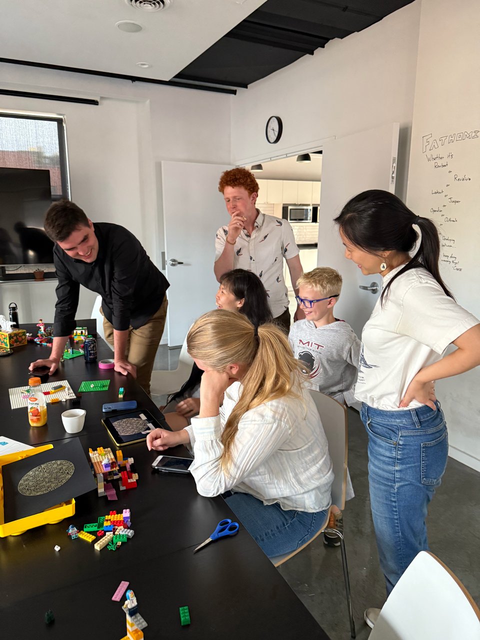 A group of people gathered around an iPad and Legos