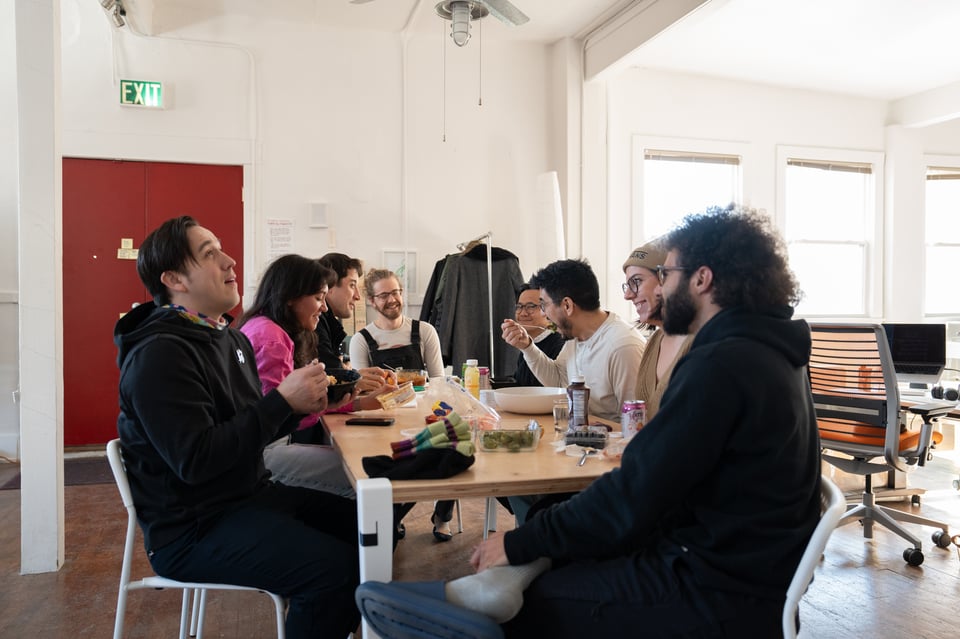 A group of people sitting at a table, one of which is eating out of a comically large bowl.