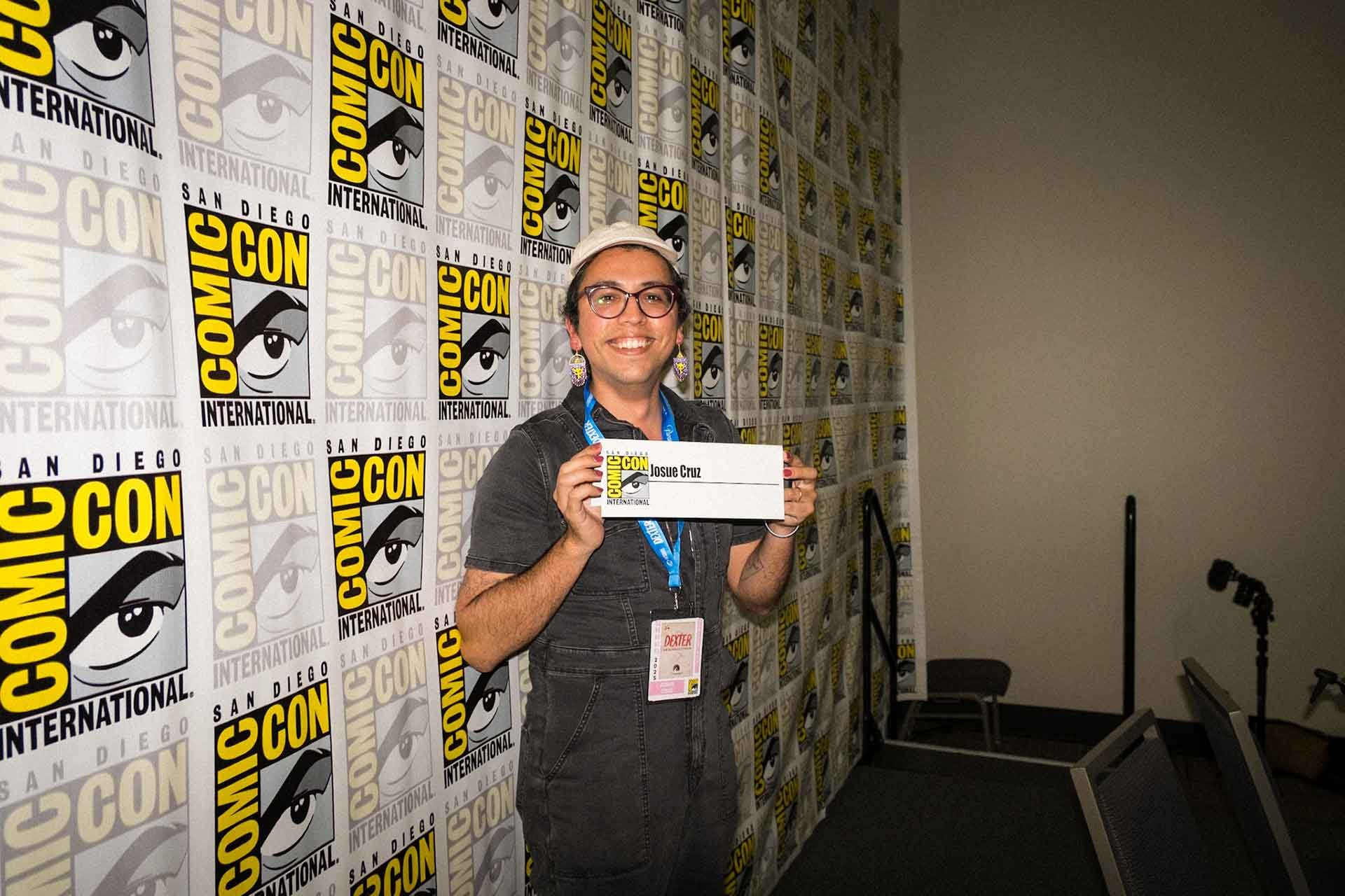 A photograph of Josue holding up their SDCC name card.