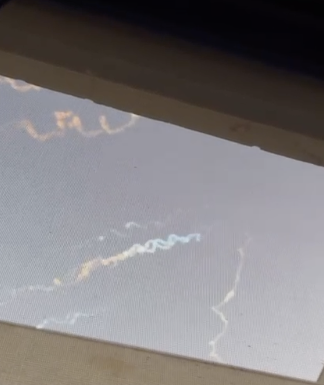 Curly contrails in the sky outside a window