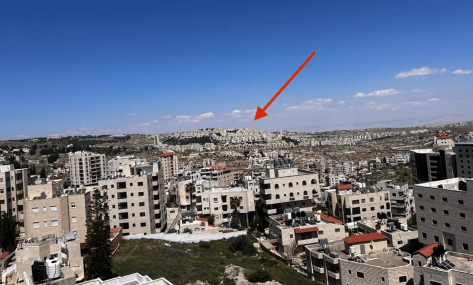 Buildings in the distance at the top of a hill, behind buildings closer to the camera