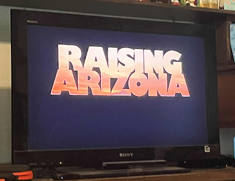 A photo of my television, which in this instant displays the title of the movie Raising Arizona.