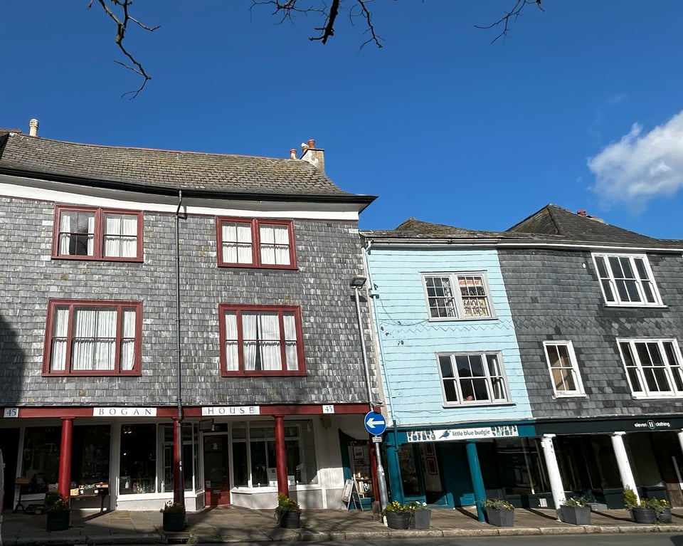 Three sixteenth/seventeenth century merchant houses. They are three storeys high, and clad in slates. the first floors of the houses overhang the pavement and are supported on stilts