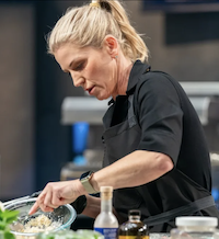 A chef stirring ingredients in a bowl
