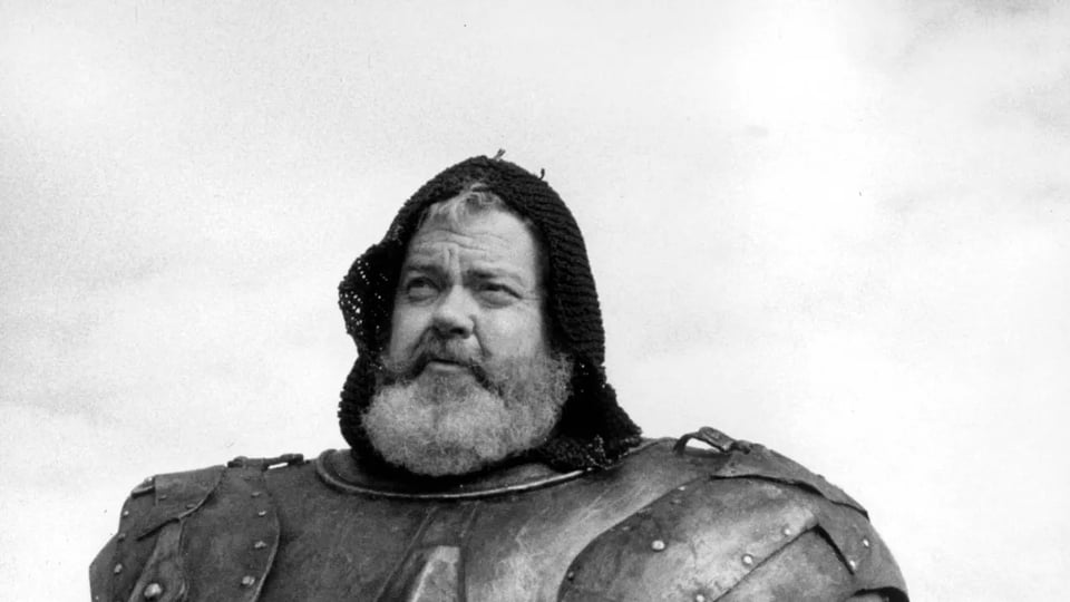 A still from Chimes at Midnight shows Orson Welles with a beard and patched armour against a grey sky.