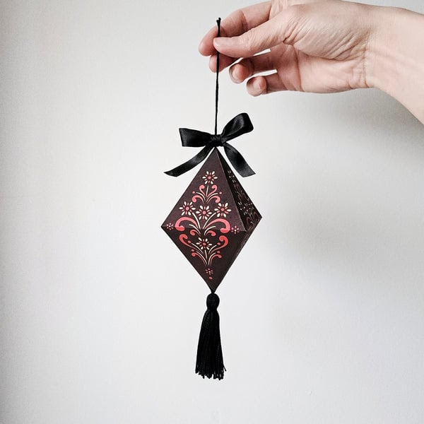 Un petit diaman en papier attaché par un cordon noir et un pompon