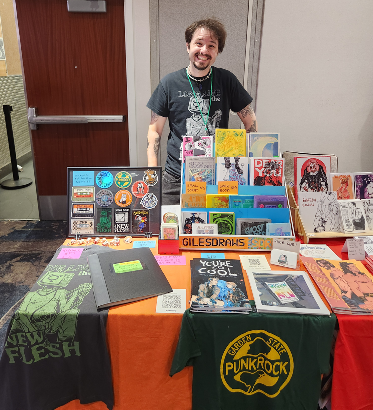 Me standing behind a table at a comic convention.
