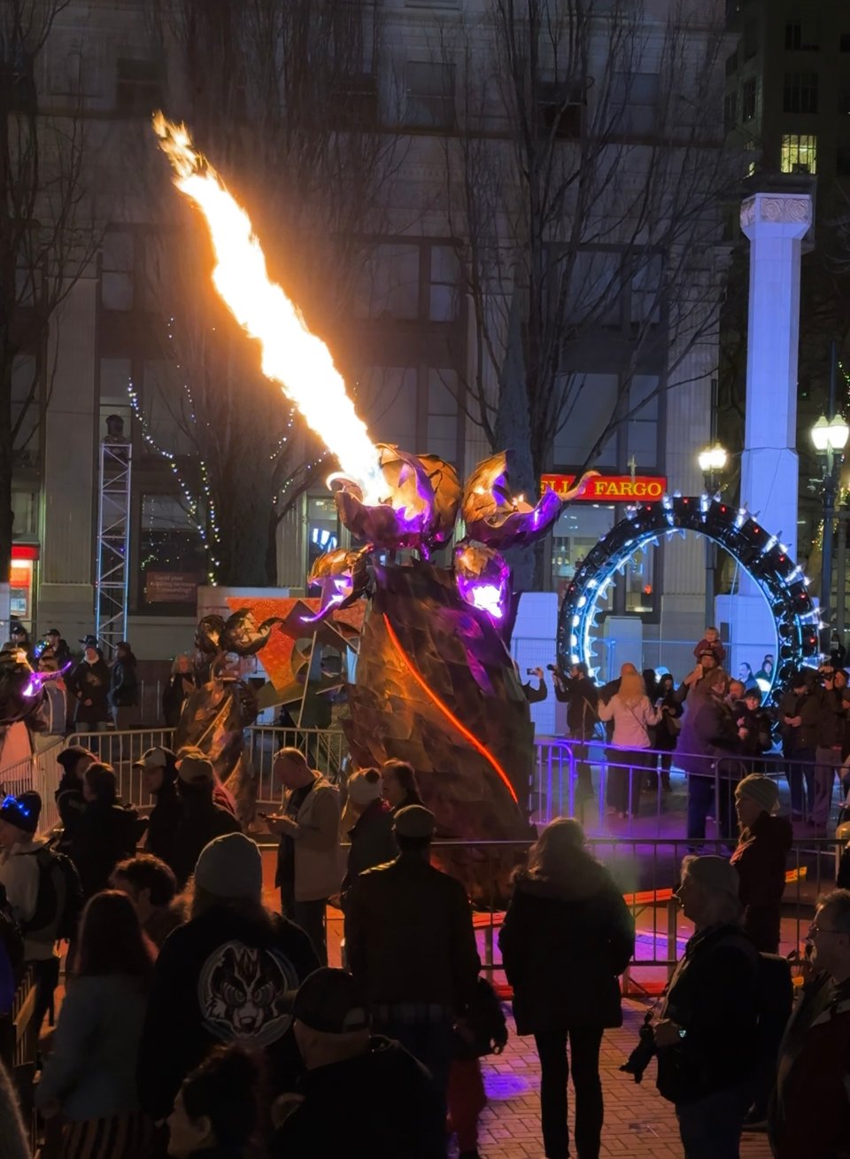Metal sculpture with fire in the center of a large crowd