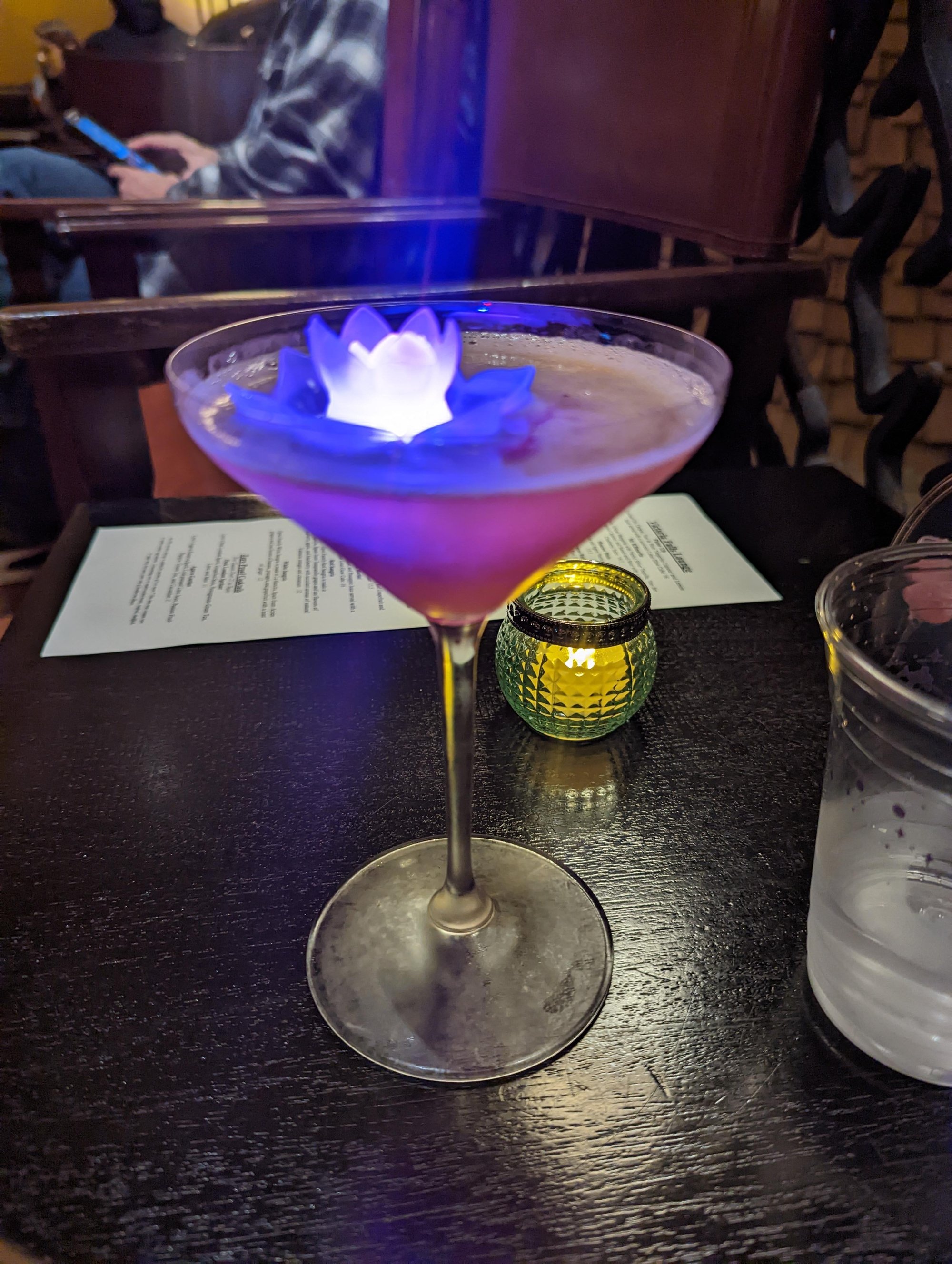 A cocktail in a martini glass with a glowing plastic lotus flower inside at Victoria Falls lounge